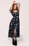 Woman wearing a black dress with celestial pattern on a plain background Woman wearing a black dress with celestial pattern on a plain background