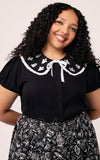 Woman wearing a black blouse with a white collar plus sized