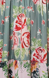 Floral patterned fabric with red roses and green leaves on a teal background.